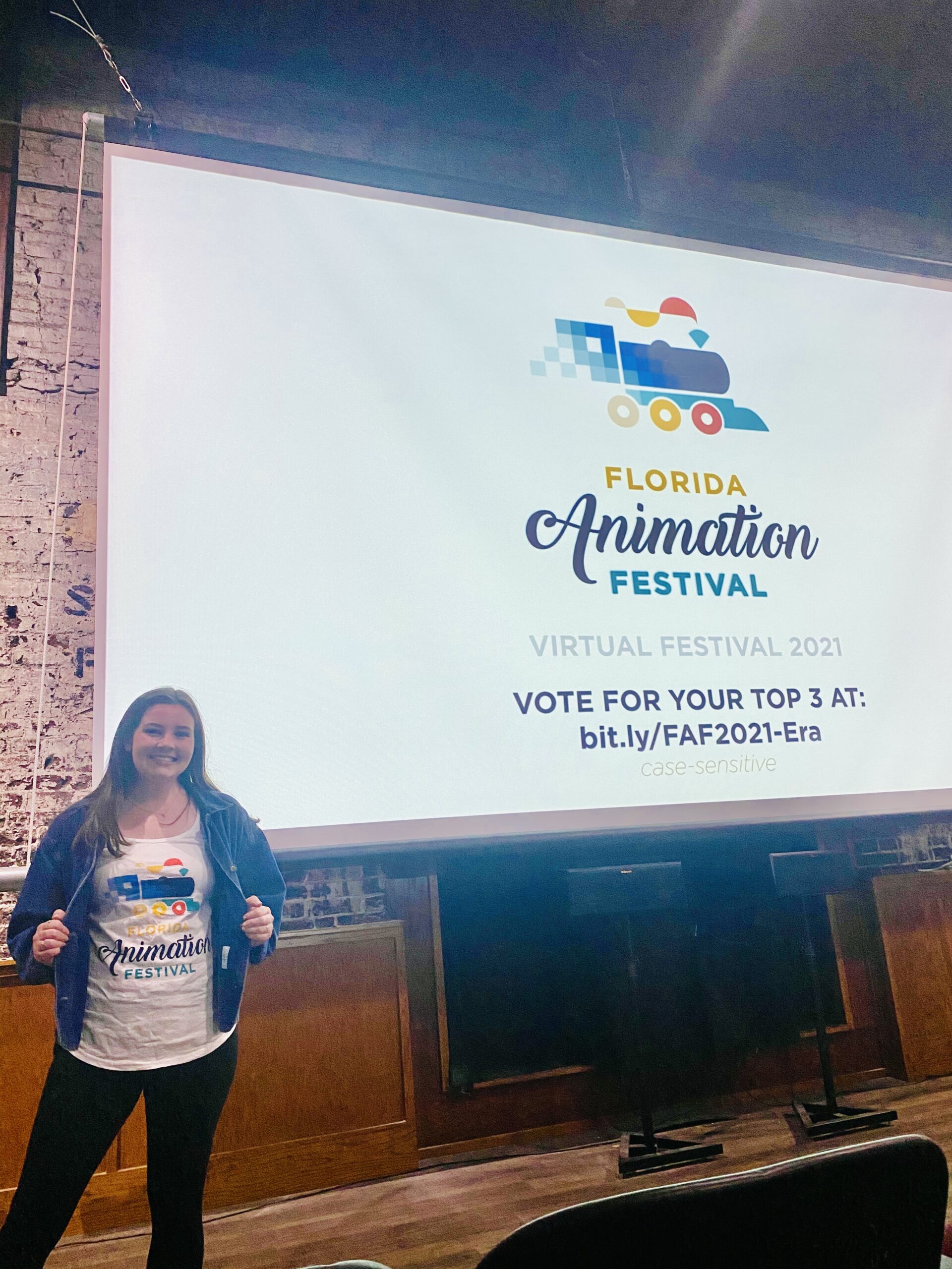 Molly Custis standing infront of a projector displaying Florida Animation Festival logo